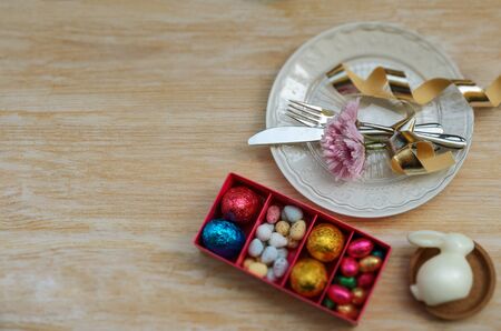 Beautiful Easter table settings decoration, white bunny, colorful chocolate eggs and plate with...