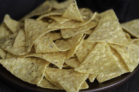 The most famous Mexican snack, nachos made con corn tortilla chips or totopos on wooden background....
