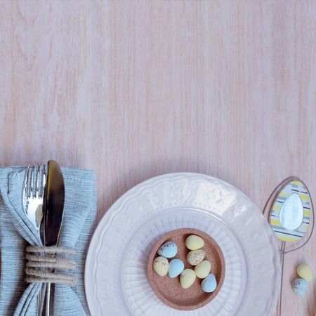 Happy Easter concept. Top view of beautiful spring table settings in pastel tone, blue linen napkin...