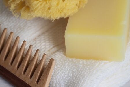 Natural sea sponge, wood hair brush, eco soap bar on white organic cotton towel. Eco sustainable...