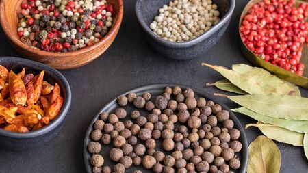 Different spices , pepper type, black ,white, pink ,green, cayenne, allspice peppercorns and bay leaf in bowls on dark background.の写真素材