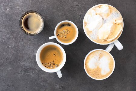 Different cups and mug with different type of coffee on dark concrete background. Top view of...