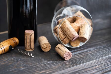 Many  used wine corks  and  corkscrew  with wine bottle on  wooden background. Wine making and wine...