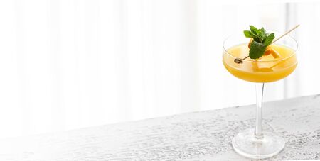 Alcoholic cocktail with stylish garnish on white concrete background. Large image for banner with copy space.の写真素材