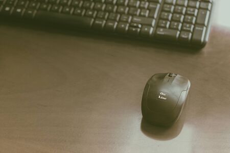 Black keyboard and computer mouse with word on line on wooden table. Working studding at distance at home concept.Toned image.Copy spaceの写真素材