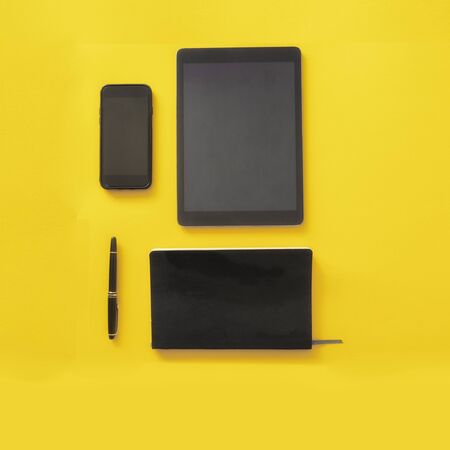 Working on line and freelancer concept. Tablet, Smatphone ,notebook and pen on bright yellow...