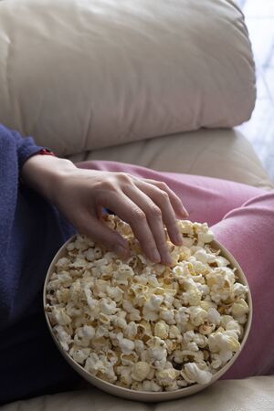 Woman hand holding popcorn bowl. Concept for relax at home  and watching tv a.の写真素材