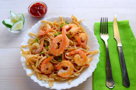 Homemade pasta with prawn, hot chili sauce and lemon on wooden background.の写真素材