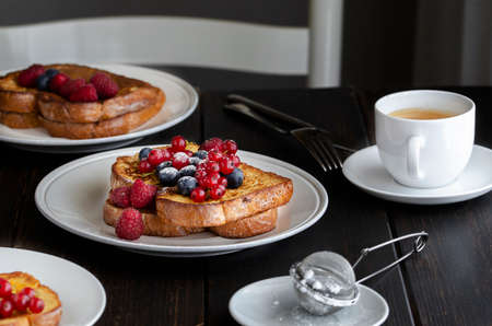 Fresh french toasts with fruit and cup of coffee on wooden table in restaurant. Good breakfast background.の写真素材