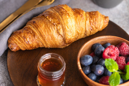 Fresh croissant, coffee with milk, berries, syrup and orange juice. Continental breakfast background.の写真素材