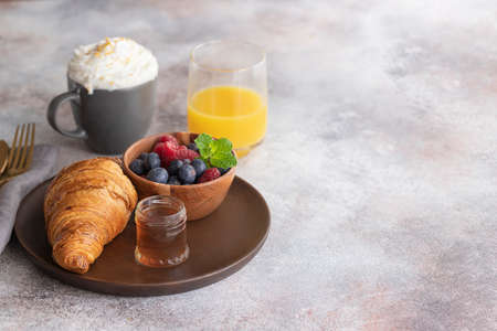 Fresh croissant, coffee with milk, fruit, syrup and orange juice. Continental breakfast background.Copy spaceの写真素材