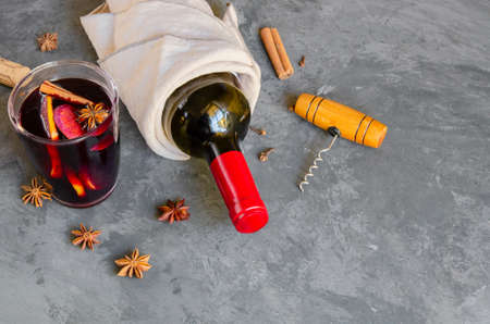 Mulled wine drink, red wine bottle and different spices on gray concrete background. Perfect winter beverage for cold days. Top viewの写真素材