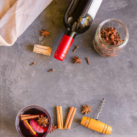 Mulled wine drink, red wine bottle and different spices on gray concrete background. Perfect winter beverage for cold days. Top viewの写真素材