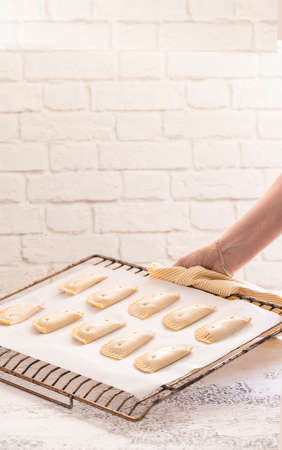 Woman put empanadillas, small filling tuna pies in roasting tray to baked pastry in oven. Typical snack in Latin American cultures and Spain. Natural atmosphere lifestyle image.の写真素材