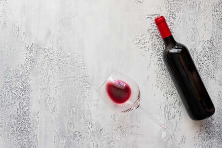 Red wine bottle with red wine glass on concrete background. Flat lay backgrund. Copy space.の写真素材