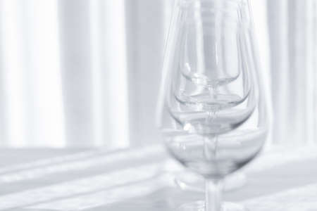 Several empty wine glasses in white gray shades on the white tableclothの写真素材