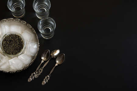 Russian beluga caviar served in a silver bowl with ice and vodka. Black caviar delicatessen background.の写真素材