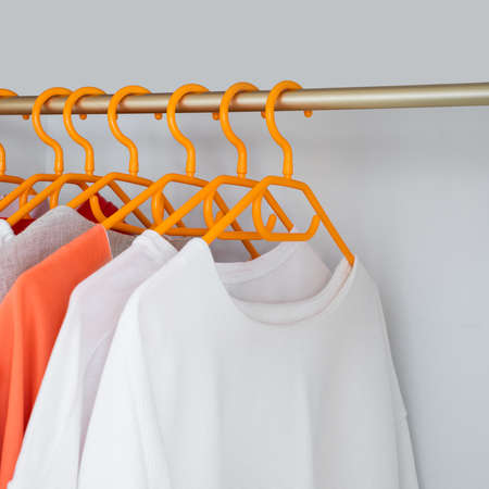 Coral and White color clothes on hangers. Several blouses and shirts for casual outfits. Fashion...