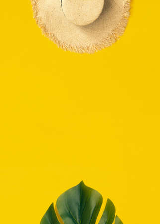Tropical palm leaf and sun straw hat on yellow background with copy space. Concept for summer vacation concept flat lay.の写真素材