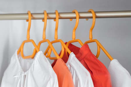 Coral and White color clothes on hangers. Several blouses, shirts for casual outfits. Fashion store background.の写真素材