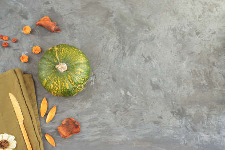 Autumn pumpkin and gold knife on cement background with orange dry leaves. Thanksgiving day and Halloween party concept.の写真素材