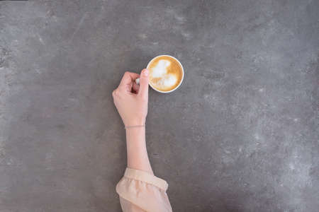 Female hand in silk blouse holding a cup of coffee with whipped cream. Love coffee concept...