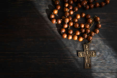 Christian cross with rosary beads into the light ray. Religion and faith concept backgroundの写真素材
