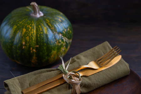 Gold cutlery with napkin and pumpkin on wooden table for Thanksgiving dinner concept. Festive autumn table settings background with Copy spaceの写真素材