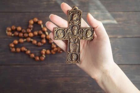 Hand holding cross, symbol of symbol of Christianity with light from above comes. Religion and faith...