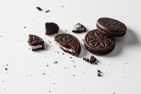 Crushed chocolate cookies with vanilla cream filling on white background.