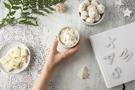 Female holding hot chocolate cup with whipped cream and Christmas decoration gray concrete background. Xmas time drink concept. scandinavian styleの写真素材