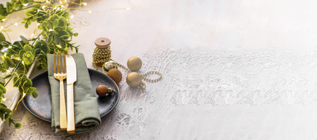 Festive table setting with ceramic plate, gold cutlery, garland and eucalypt brunch. Merry Christmas and Happy New Year celebration concept. Bannerの写真素材