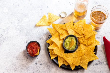 Famous Mexican snack, nachos with guacamole, red chilli sauce and beer on cement background. Top view.の写真素材