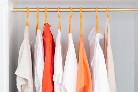 Coral and White color clothes on hangers. Several blouses, shirts for casual outfits. Fashion store background.の写真素材