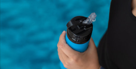 Female hands holding sports bottle. Drinking water during exercise concept.Large backgrund for bannerの写真素材