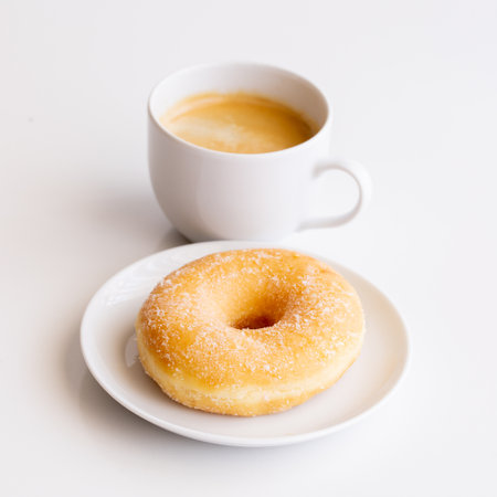 Cup of coffee with classic sugar donut on white background.Copy spaceの写真素材