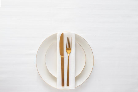 Gold cutlery knife and fork on the white plate for restaurant dinner concept.の写真素材