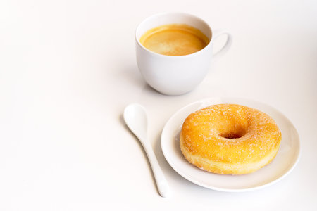 Cup of coffee with classic sugar donut on white background.Copy spaceの写真素材