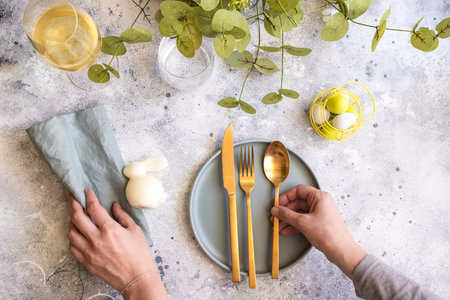 Happy Easter table setting: bunny, mint green plate and woman hands with gold cutlery. Scandinavian style background with copy spaceの写真素材