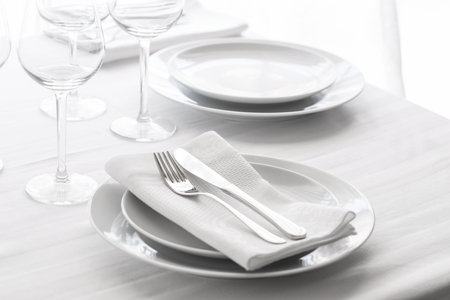 Table setting with white plates, silver cutlery and glasses for elegant festive dinner. Dining concept background.の写真素材