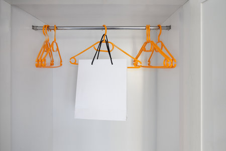 White paper shopping in empty wardrobe with hangers without clothes. nothing to wear concept backgroundの写真素材