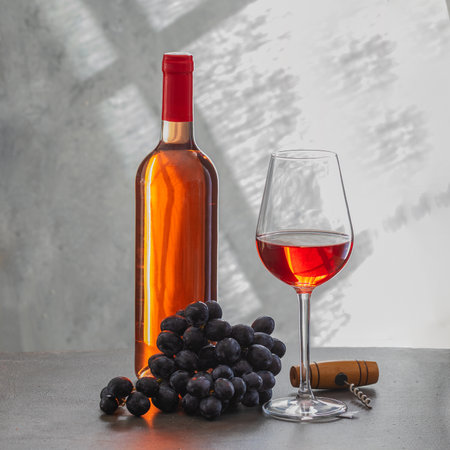 Rose wine bottle, wine glass and grape on gray concrete background. Wine making and wine tasting concept.の写真素材