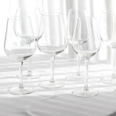 Several empty wine glasses in white gray shades on the white tablecloth for abstract backgroundの写真素材