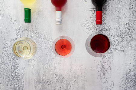 Red, rose and white wine bottles and different wine glasses on concrete background with copy space. top view.の写真素材