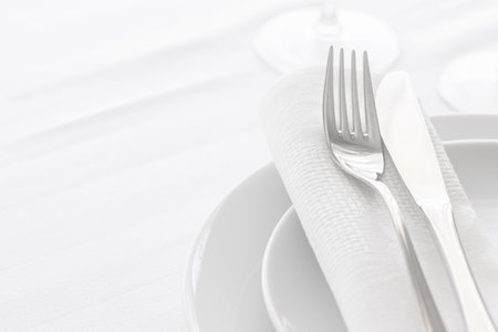 Close up of silverware fork and knife with napkin on the plate. Copyspace. Restaurant dining concept.の写真素材