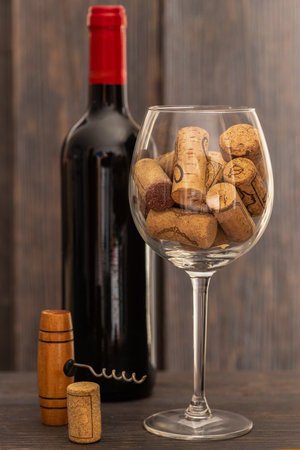 Red wine bottle, wine glass with wine corks and corkscrew on wooden table. Drinking wine concept.の写真素材