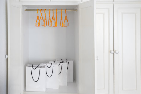 White shopping bags in empty wardrobe with hangers without clothes. Updating wardrobe and shopping conceptの写真素材