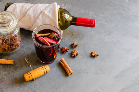 Mulled wine drink, red wine bottle and different spices on gray concrete background. Perfect winter beverage for cold days. top viewの写真素材