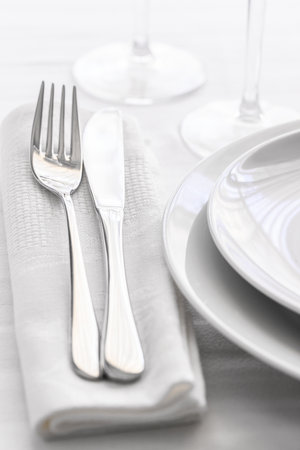 Close up of silverware fork and knife with napkin on white porcelaine plate. Copyspace. Restaurant dining concept.の写真素材