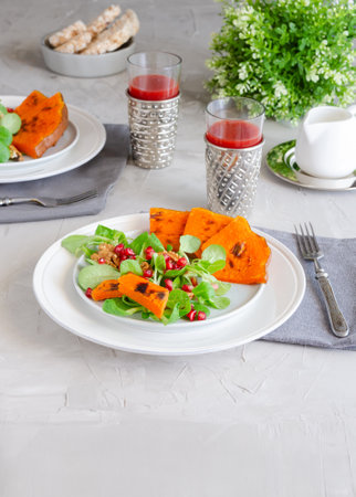 Fresh autumn salad with grilled pumpkin and lettuce with pomegranate seeds. Healthy nutritious vegetarian diet.の写真素材